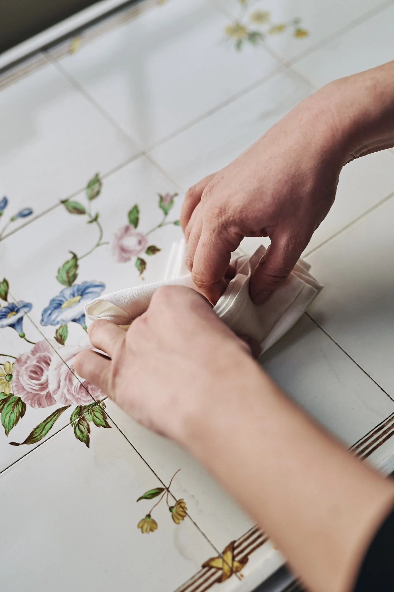 Schritte vier und fünf des Faltens mit weißer Serviette in Form eines Fächers.