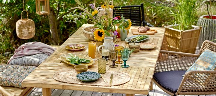 Tischdeko für den Sommer – Sonnenblumen, farbenfrohes Geschirr von Bloomingville in einem grünen Garten.