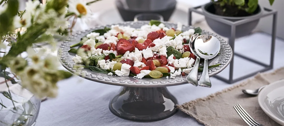 Frischer Sommersalat mit Erdbeeren und Feta-Käse, serviert auf einer Kuchenplatte von PotteryJo zum Sommermittagessen.