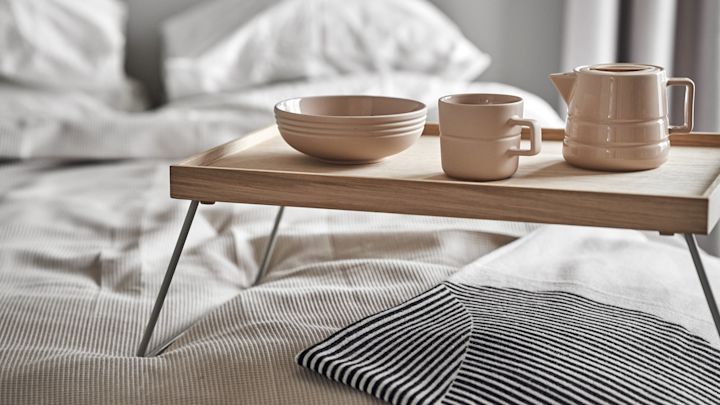 Lagom bedeutet auch, entspannt in den Tag zu starten. Hier stehen eine Tasse, eine Kanne und eine Schüssel aus der Lines-Kollektion von NJRD auf einem Frühstückstablett im Bett.