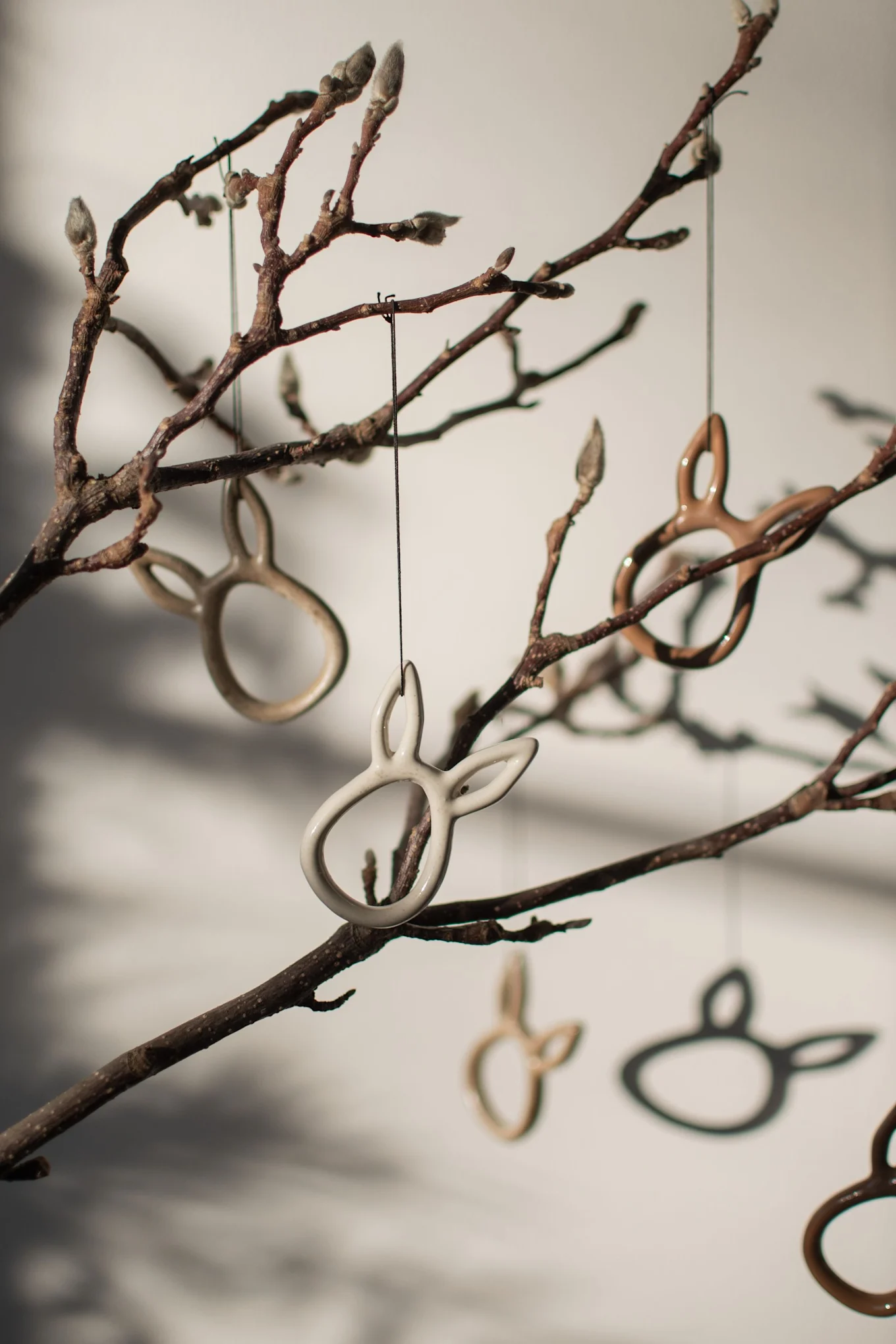 Die hasenförmigen Sprinkle rabbit Easter Anhänger von DBKD hängen an einem Strauch.