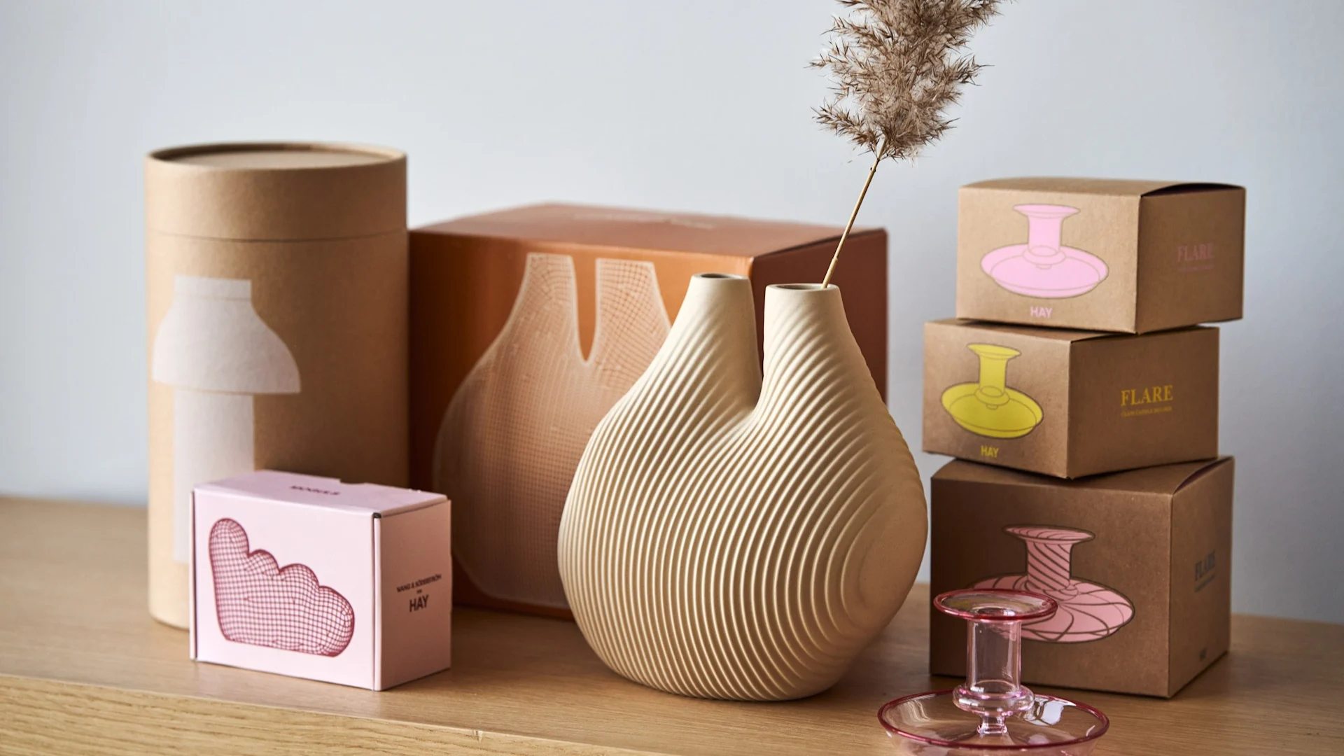 Die W&S Chamber Vase in Beige von HAY inmitten von bunten Produktboxen.