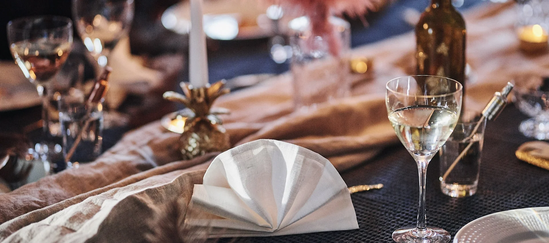 Zu einem Fächer gefaltete weiße Leinenserviette auf einem gedeckten Tisch.