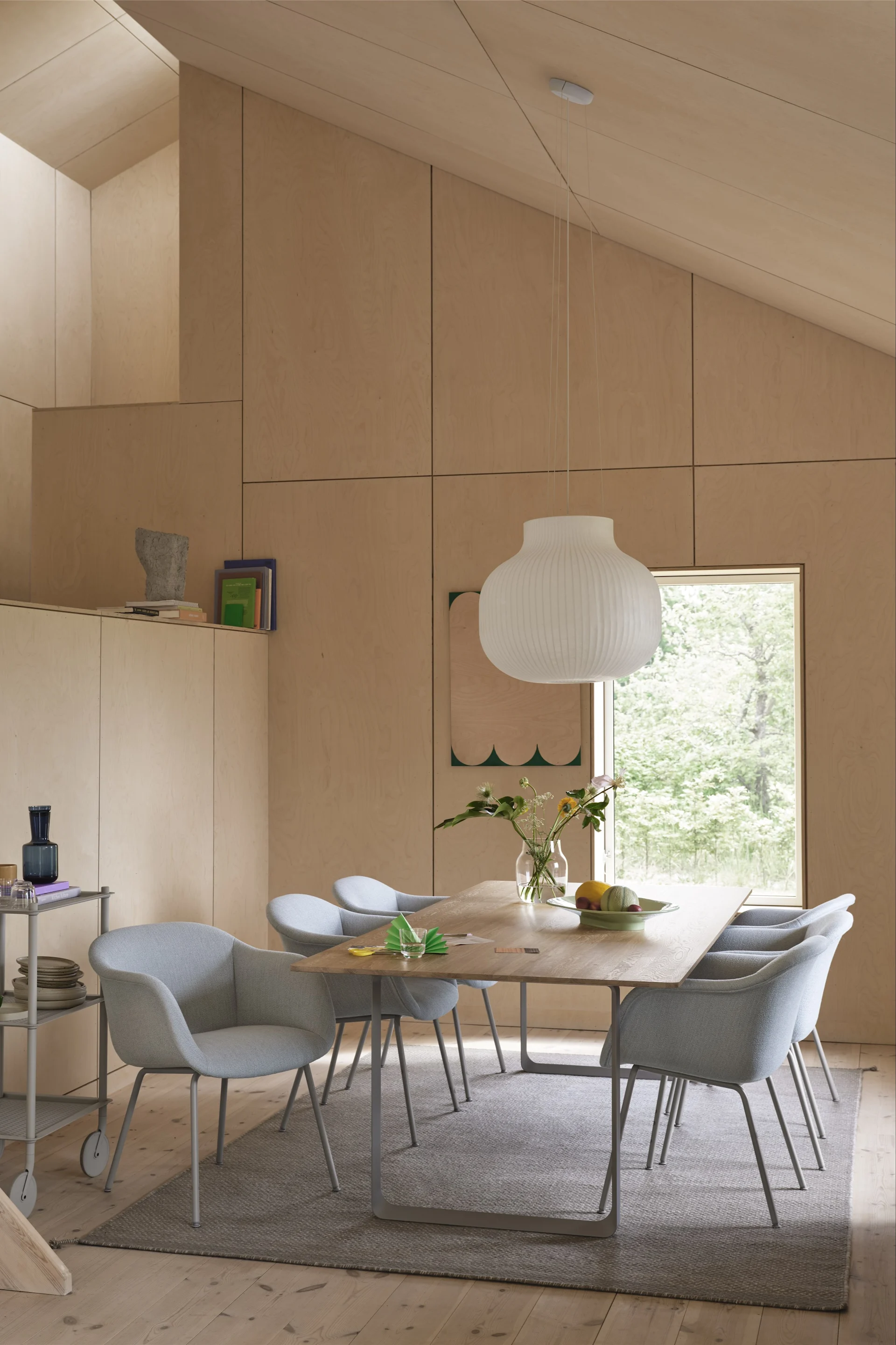 Teppiche für den Essbereich: Der graue Ply Wollteppich von Muuto liegt in einem skandinavisch eingerichteten Esszimmer mit hellblauen Stühlen und viel Holz.