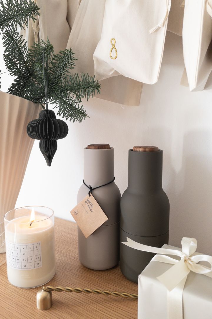 Geschenkideen zu Weihnachten: Verschenken Sie die Gewürzmühlen Bottle Grinder von Audo Copenhagen, welche hier von einer Kerze, einer Vase mit Tannengrün und einem Adventskalender von Ferm Living auf einem Tisch stehen.