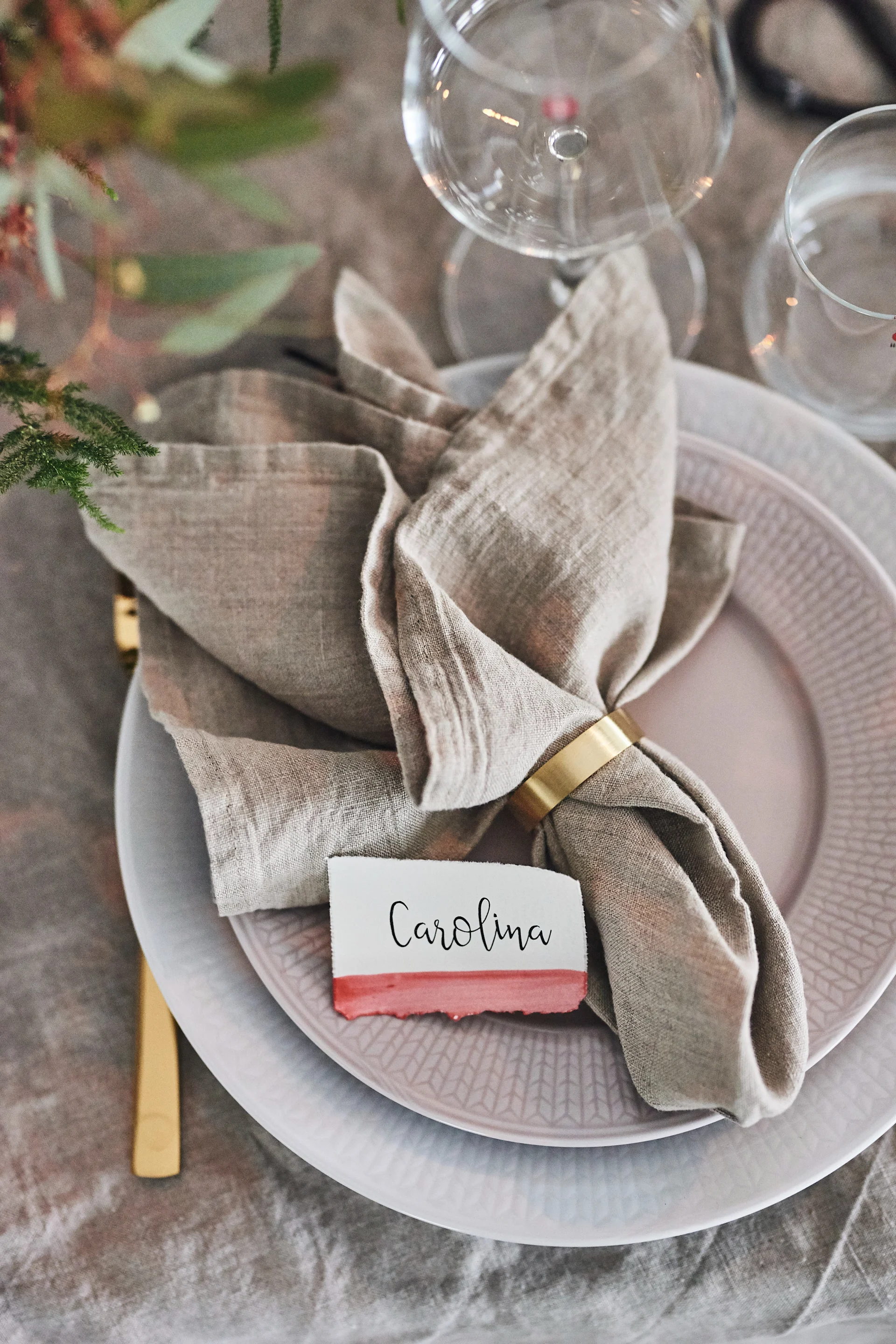 Ein Tipp zum Falten von Servietten mit einem Serviettenring ist die Kombination eines Serviettenrings aus Messing mit einer beigen Leinenserviette.