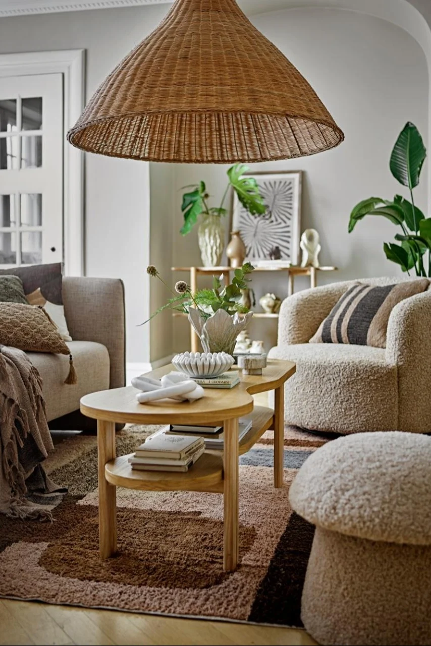 Boho Deko zeichnet sich unter anderem durch Rattan-Elemente und Pflanzen aus. Hier sehen Sie ein im Boho-Stil dekoriertes Wohnzimmer mit Produkten von Bloomingville.