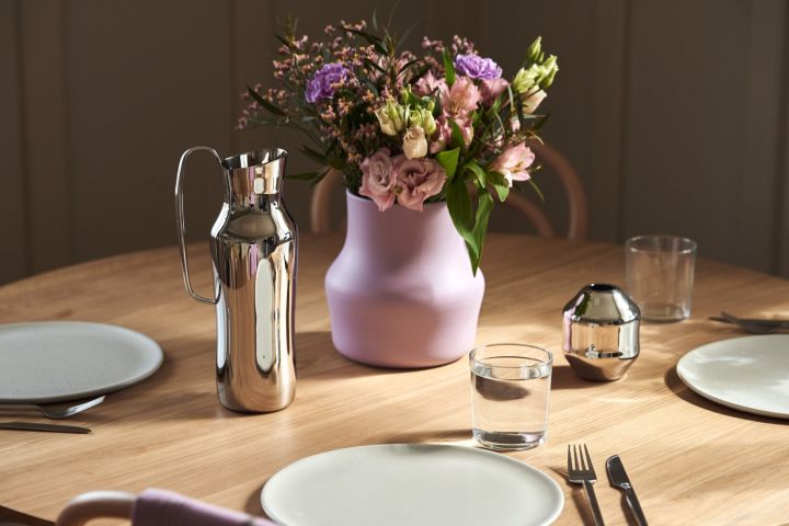 Die Karaffe aus poliertem Edelstahl steht neben der fliederfarbenen Vase Dorotea, die Monica Förster für Gense entworfen hat. 