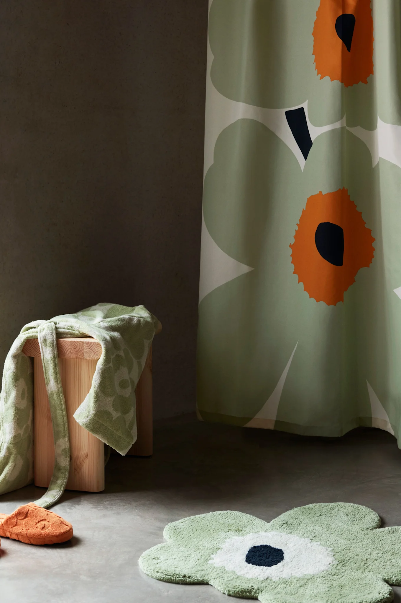 Badezimmerdekor mit grünem Blumen-Duschvorhang, Badematte, Handtuch auf Hocker und orangefarbenem Hausschuh.