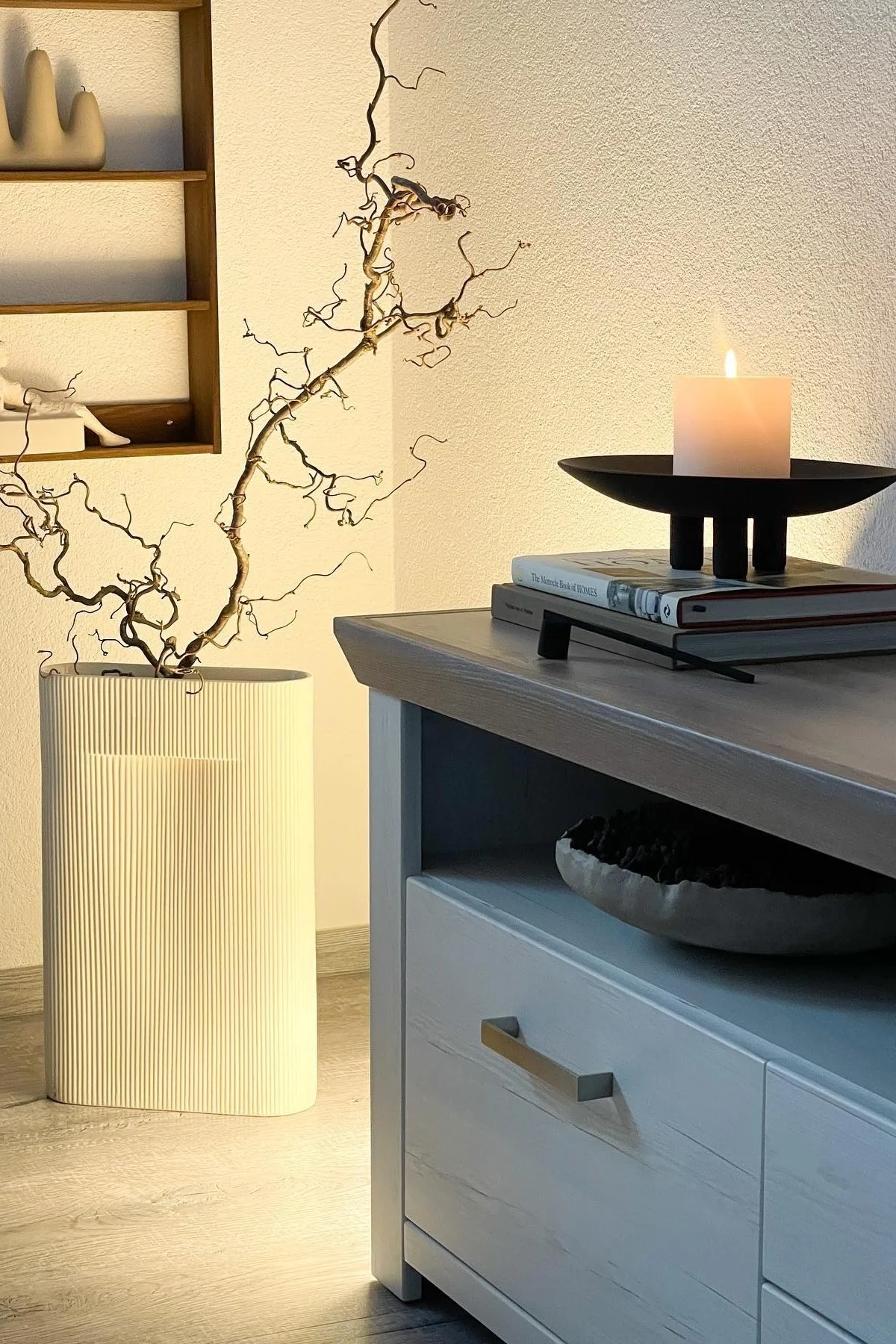 Japandi: Hier sehen Sie die große Ridge-Vase von Muuto, bestückt mit ein paar Zweigen neben einem Lowboard, dekoriert mit der Duck-Schale von 101 Copenhagen.