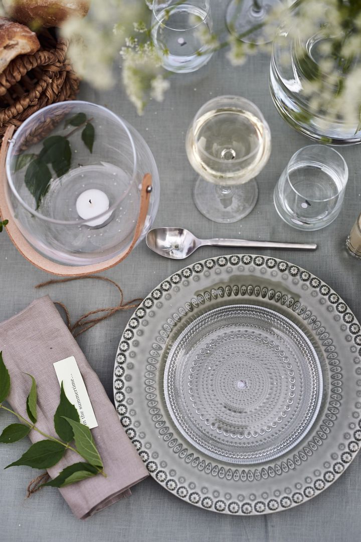 Bei der Gartenparty ist der Tisch mit einem grünen Teller von PotteryJo und einer klaren Glasplatte von Iiittala auf einer grünen Leinentischdecke und Gläsern gedeckt. 