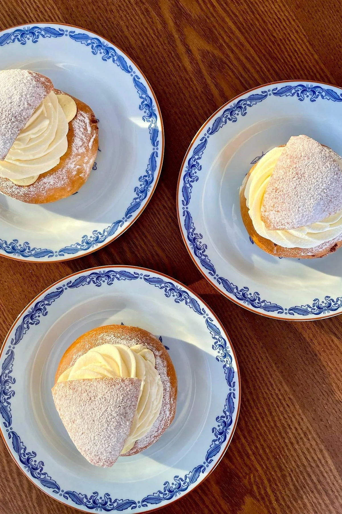 Auf einem Tisch stehen drei Teller mit Semlor, typisch schwedischem Gebäck.