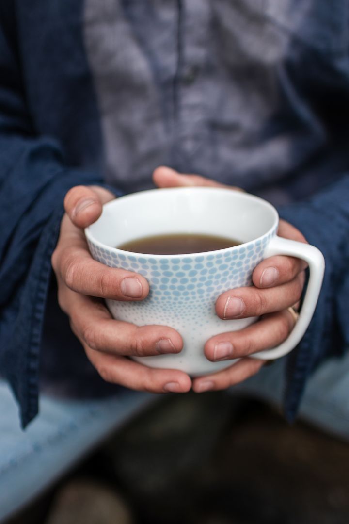 Eine heiße Tasse Tee im Freien, hier die Osean Tasse von Wik & Walsoe, die von zwei Händen umschlossen wird, sollte unbedingt auf Ihrer Herbt To-do-Liste stehen.