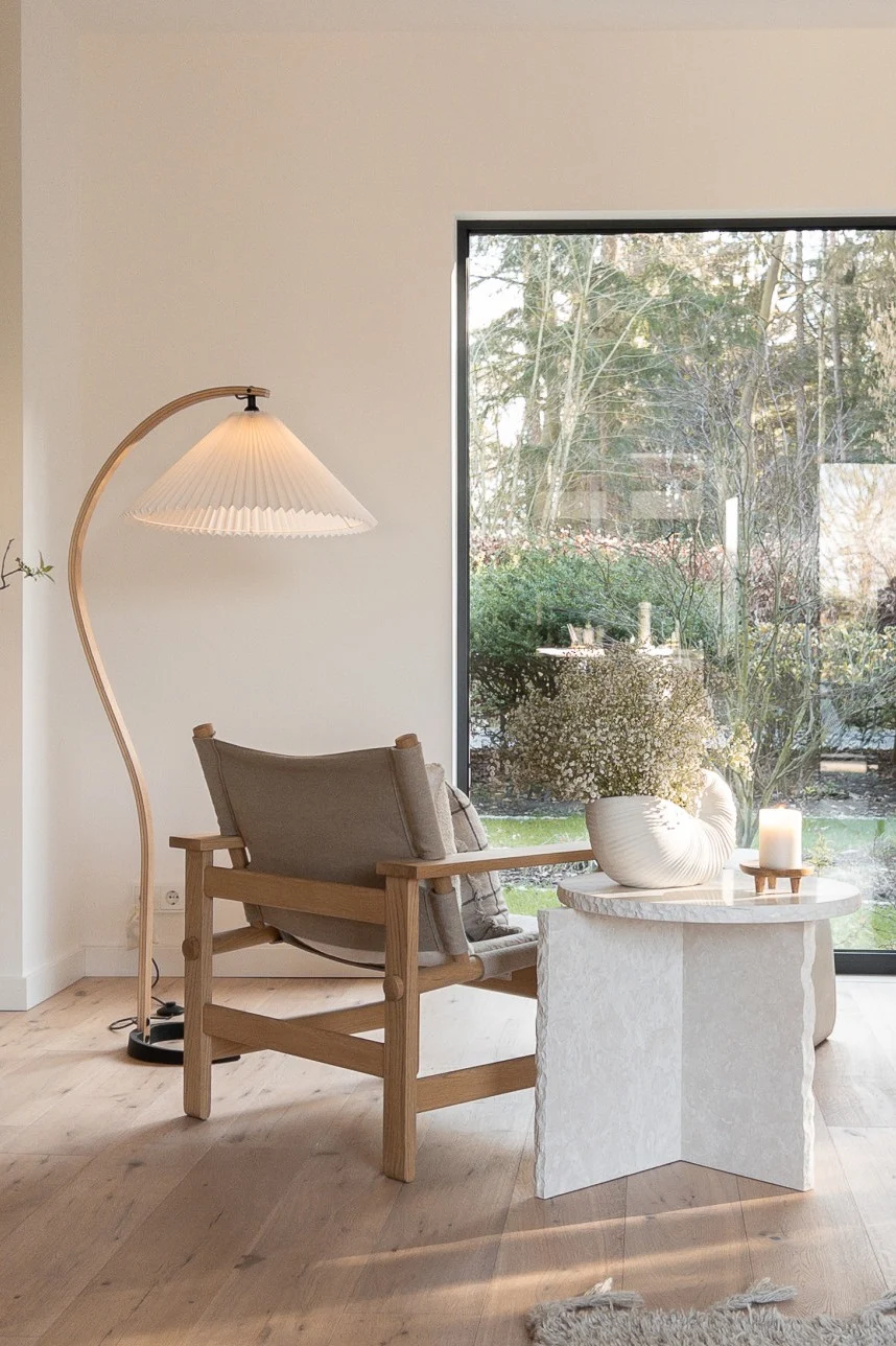 Spielen Sie mit natürlichem Licht in Ihrem skandinavischen Zuhause. Hier sehen Sie eine gebogene Stehleuchte von Gubi und den Mineral Beistelltisch von ferm Living. 