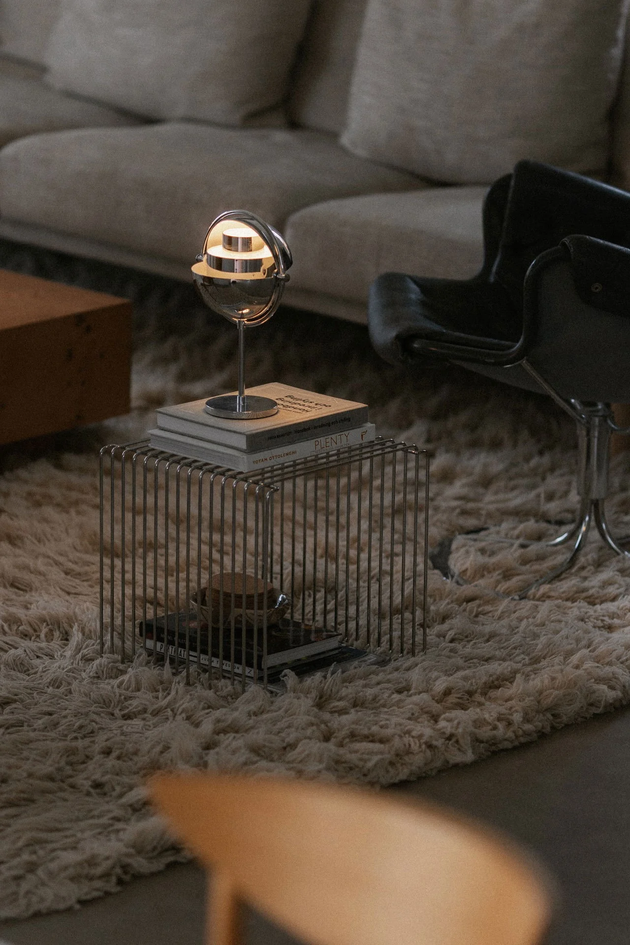 Skandinavische Lampen: Die chromfarbene Multi-Lite-Tischleuchte von Gubi steht in einem Wohnzimmer auf einem Panton Wire Regal.