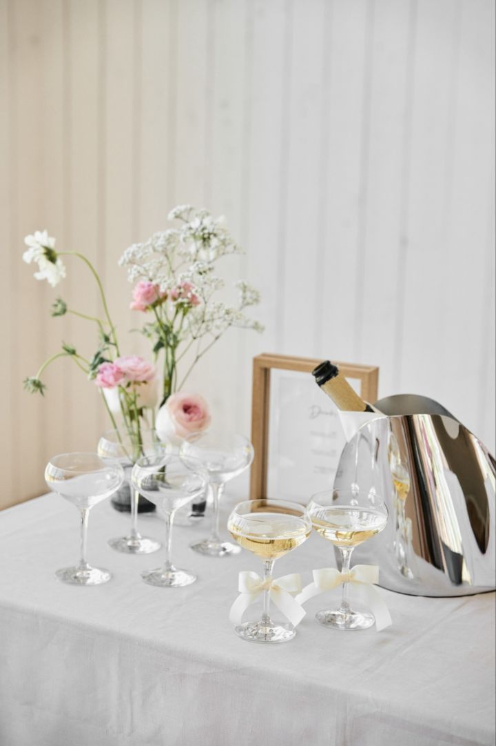 Diese einzigartige Hochzeitsidee ist ideal für Hochzeiten im Freien. Hier sehen Sie eine Getränkestation mit einem Weinkühler und einem Set More Coupe-Gläser von Orrefors. 