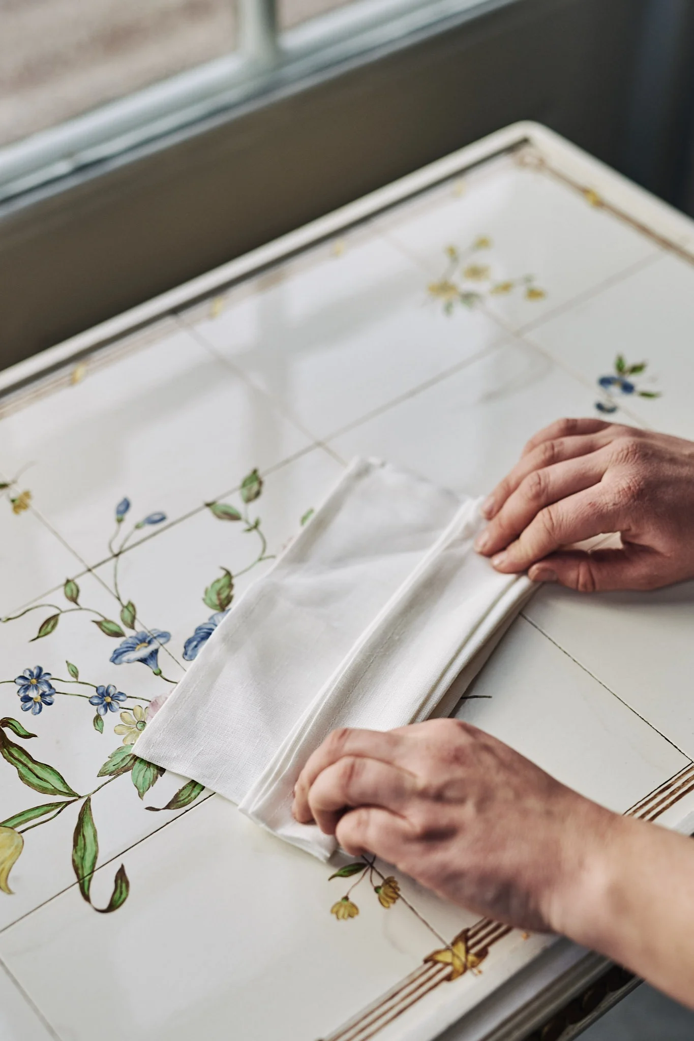 Serviettenfaltung mit weißer Leinenserviette in Form eines Fächers.