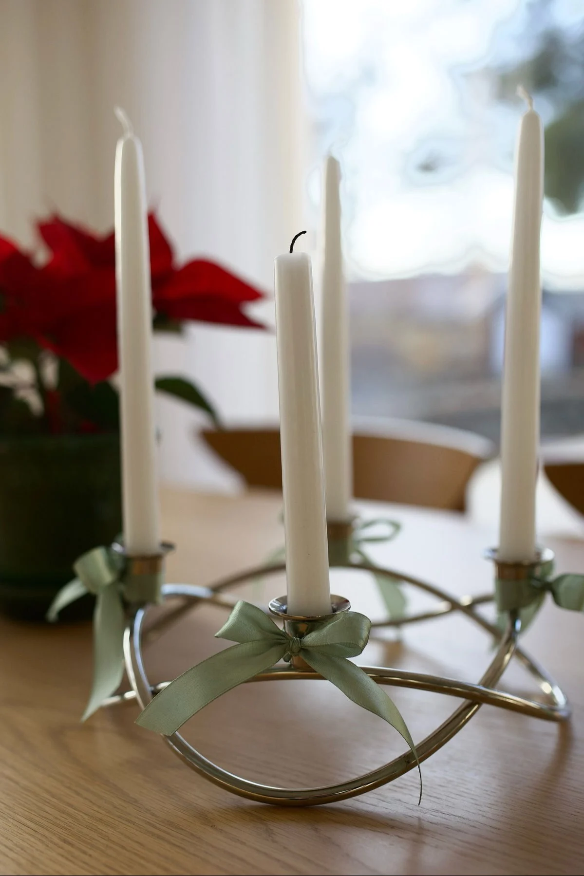Der silberne, mit Schleifen dekorierte Season Kerzenhalter von Georg Jensen steht auf einem Tisch.