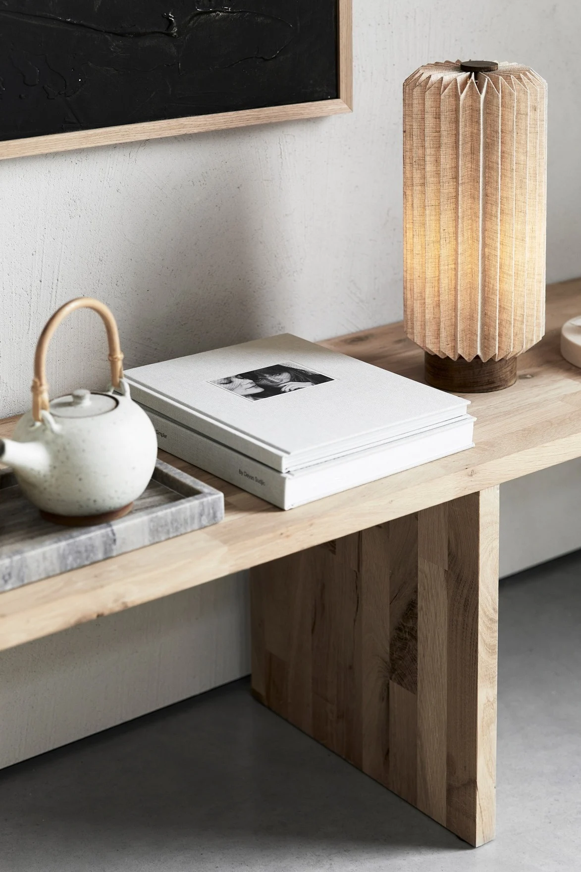Japandi: Eine Bank mit einer Teekanne, Büchern und der Alba Tischlampe von Watt & Veke.