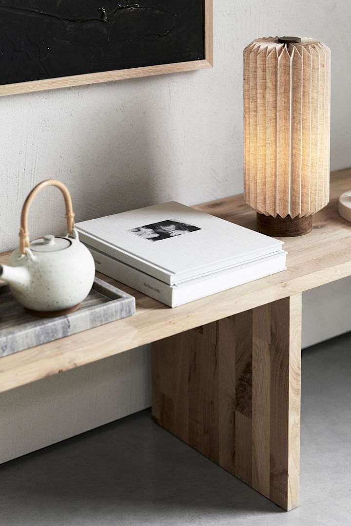 Japandi: Eine Bank mit einer Teekanne, Büchern und der Alba Tischlampe von Watt & Veke.