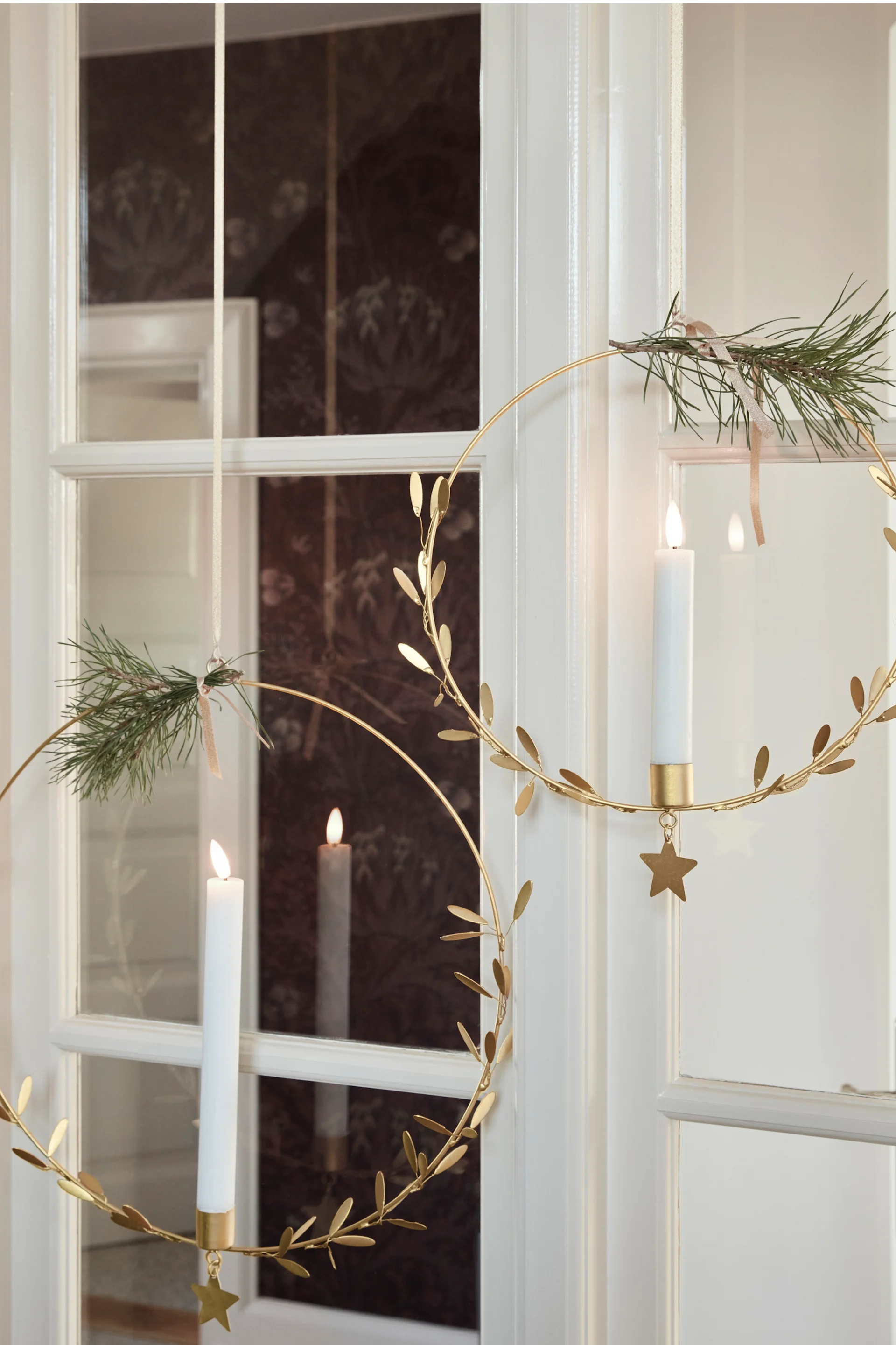 Dekorieren Sie Ihre Fenster weihnachtlich, zum Beispiel mit den Misten Kerzenhaltern von House Doctor, die hier in einem Fenster hängen.