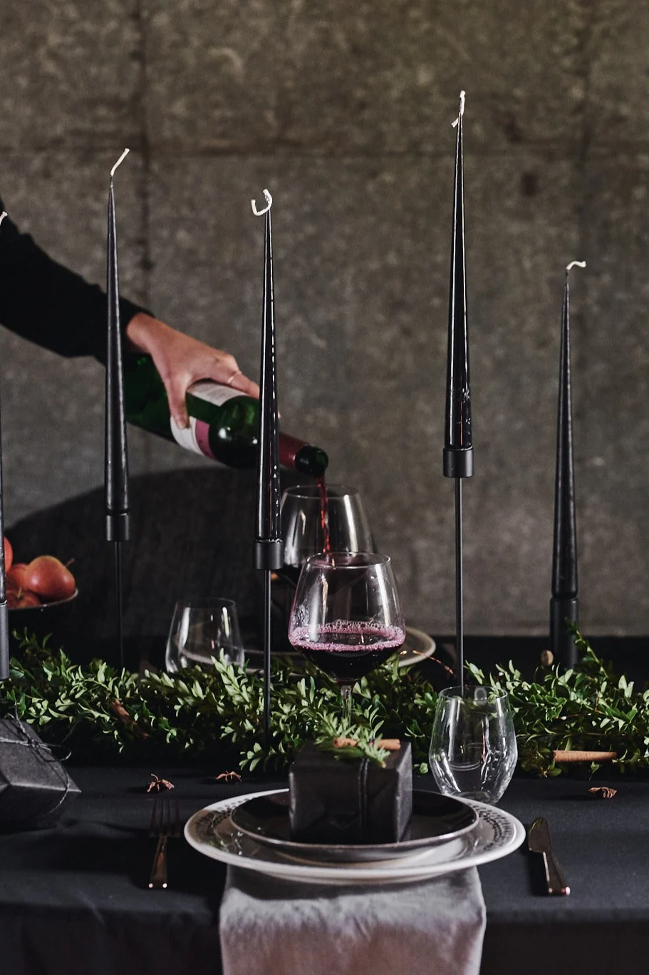 Eine dramatische Tischdeko in Schwarz: Hier sehen Sie den Kerzenhalter von Cooee Design und die schwarzen Kerzen von Esther & Eric auf einem schwarz gedeckten Tisch.