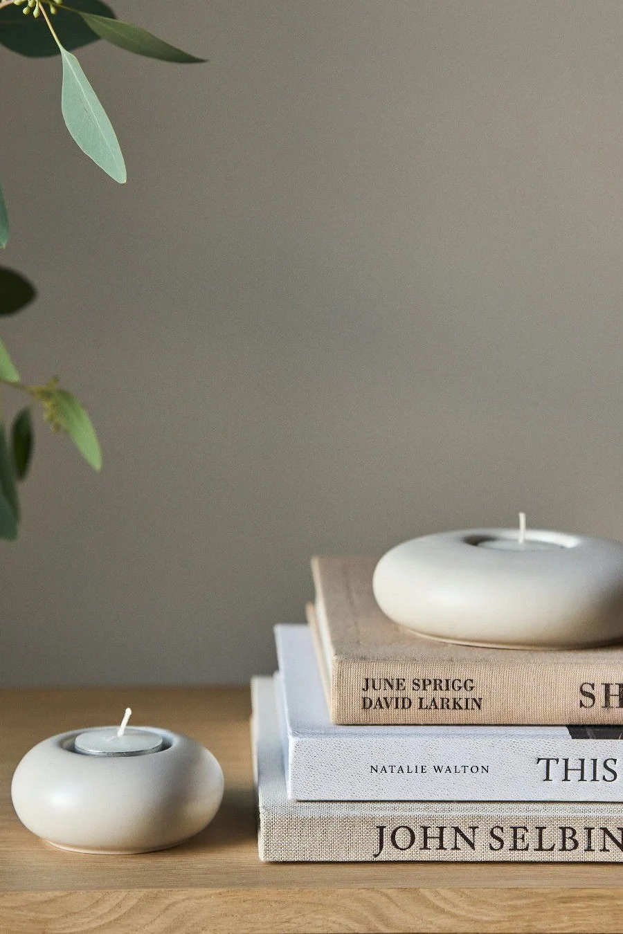 Lagom: Ein Stapel mit Büchern, auf dem ein Stone Windlicht von Scandi Living steht.