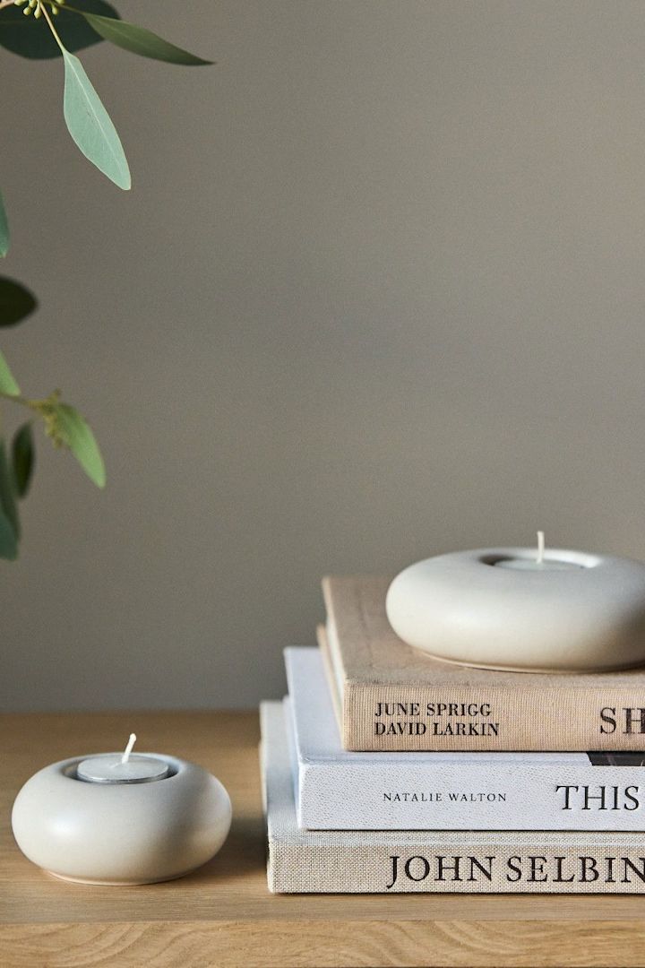 Lagom: Ein Stapel mit Büchern, auf dem ein Stone Windlicht von Scandi Living steht.