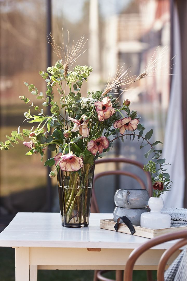 Genießen Sie ein Tasse Kaffee und atmen Sie den Duft der frischen Blumen von Blombruket ein, die in einer Vase von Iittala platziert sind.